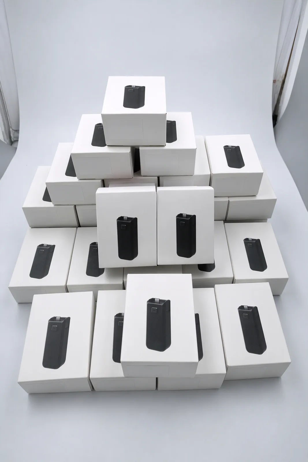 Boxed battery handles stacked in a pyramid on a white table