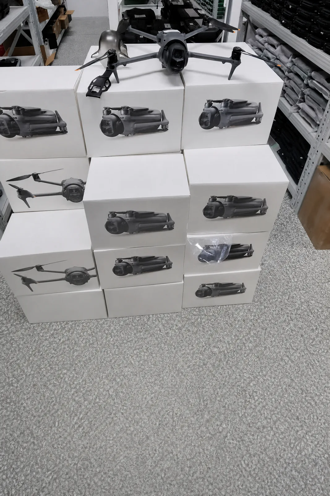 A grey DJI drone with its arms unfolded, standing on a stack of boxed drones